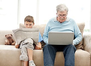 Großvater sitzt mit Enkel auf einem Sofa