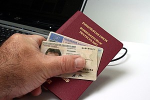 Foto einer Hand, die einen Ausweis und einen Pass festhält
